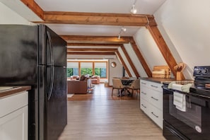 A modern kitchen with a black refrigerator, wooden beams, and a dining area with a table and chairs.