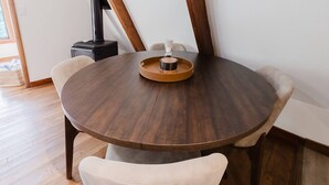 Ein runder Holztisch mit einer Ablage in der Mitte, umgeben von Stühlen.