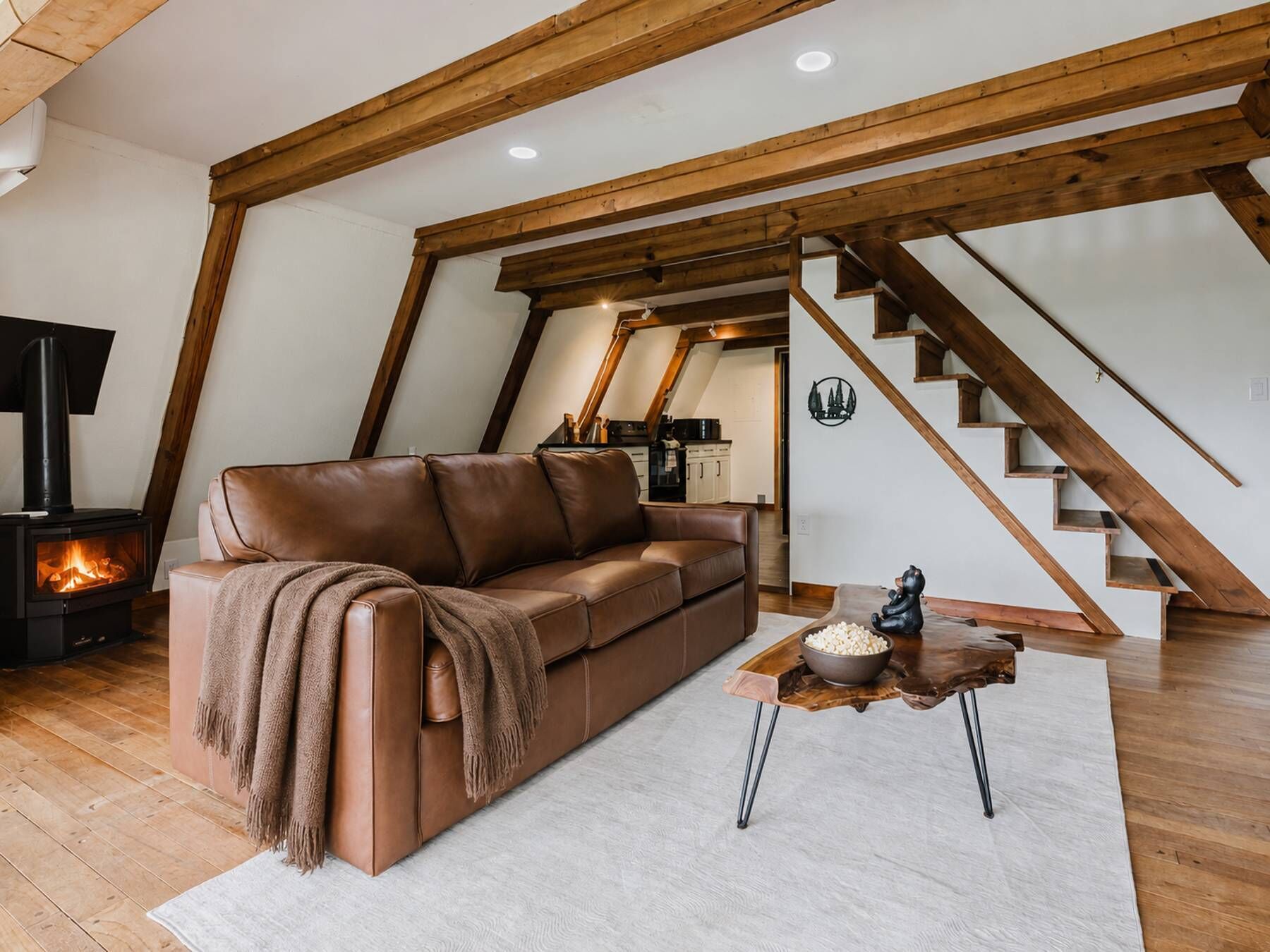 A cozy living room with a leather sofa, a coffee table, and a fireplace.