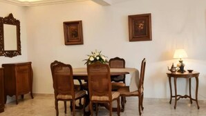 A dining area with a table set for four, surrounded by chairs, with a mirror and framed pictures on the walls. - Central luxury apartment 3 bedrooms (Cairo Governorate)