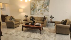A living room with a sofa set, a coffee table with books, a floor lamp, and a large abstract painting on the wall. - Central luxury apartment 3 bedrooms (Cairo Governorate)
