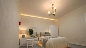 A bedroom with a bed, bedside table, lamp, and a hanging light fixture. - Central luxury apartment 3 bedrooms (Cairo Governorate)