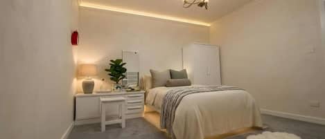 A bedroom with a bed, bedside table, lamp, and a hanging light fixture.