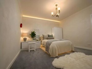 Un dormitorio con cama, mesita de noche, lámpara y lámpara colgante.