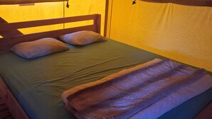 A bed with a canopy, pillows, and a blanket.