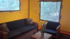A room with a wooden floor, a sofa, a coffee table, and two windows with curtains.