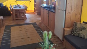 A compact living space with a dining area, kitchenette, and a sofa with a cushion.