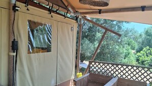 A covered outdoor seating area with wooden furniture and a woven light fixture.