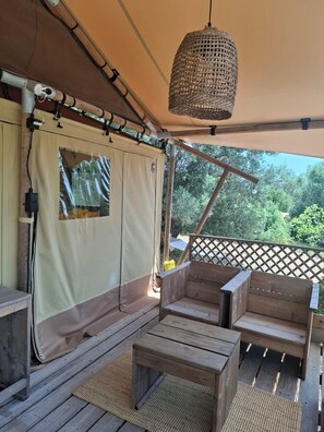 A covered outdoor seating area with wooden furniture and a woven light fixture.