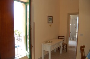 A room with a white table and chairs, a door leading to a balcony, and a framed picture on the wall. - Lugrà Apartment with Sea View, Wi-Fi, and Air Conditioning (Santa Maria di Castellabate)