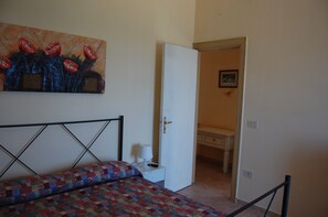 A bedroom with a bed, a desk, and a door leading to another room. - Lugrà Apartment with Sea View, Wi-Fi, and Air Conditioning (Santa Maria di Castellabate)