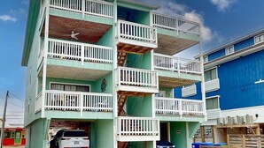 A multi-story building with balconies, a garage, and a blue exterior wall. - Reefs 7-3, Dog Friendly Beachfront Property, just steps away from the beach (Carolina Beach)