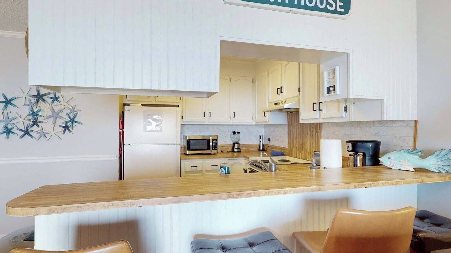 A compact kitchen with white cabinets, a microwave, and a coffee maker.