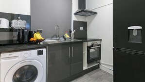 A modern kitchen with a washing machine, a water dispenser, and a sink. - Studio Sleeps 2 With Parking (Thornton Heath)