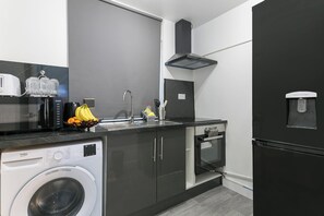 A modern kitchen with a washing machine, a water dispenser, and a sink. - Studio Sleeps 2 With Parking (Thornton Heath)