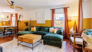 A living room with a sectional sofa, a wooden coffee table, and a dining area with a table and chairs. - Tranquil Downtown Retreat w Private Pool & Hot Tub (Austin)