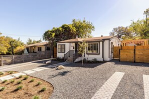 Ein Wohnhaus mit Schotterauffahrt, Holzzaun und kleinem Garten.
