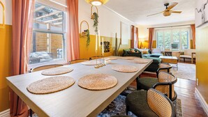 A dining area with a long table, woven placemats, and a hanging light fixture. - Tranquil Downtown Retreat w Private Pool & Hot Tub (Austin)