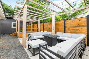 Un espace extérieur aménagé, abrité par une pergola, avec une table et un canapé.
