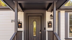 A house entrance with a dark door, a porch with a railing, and a mailbox on the wall. - Tranquil Downtown Retreat w Private Pool & Hot Tub (Austin)