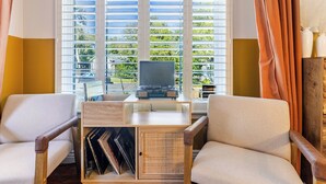 A room with a desk, two chairs, a television, and a window with blinds. - Tranquil Downtown Retreat w Private Pool & Hot Tub (Austin)
