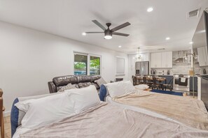 Una camera da letto con due letti, un ventilatore a soffitto, un'area pranzo con tavolo e sedie e una cucina completa di elettrodomestici.