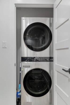 A stainless steel laundry room with two large washing machines, a control panel, and a water heater. - 4BR Downtown Austin Stay | Pool & Backyard Games (Austin)