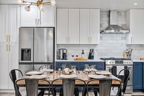A modern kitchen with white cabinets, stainless steel appliances, and a dining area set for six.