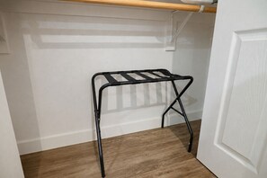 A corner of a room with a white door, a wooden floor, and a black metal shelf unit.