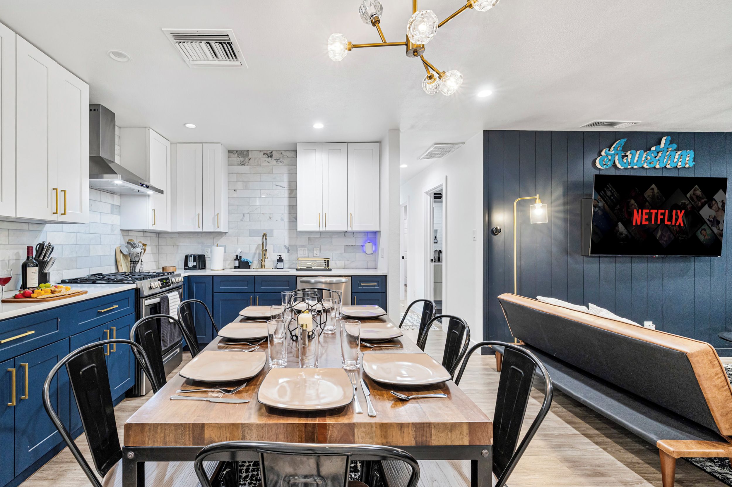 A modern kitchen with white cabinets, a dining table set for six, and a Netflix sign on the wall.