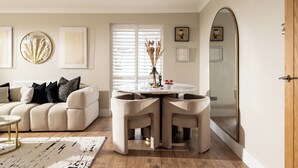 Un salon avec un canapé, une table de salle à manger ronde entourée de chaises et un grand miroir.