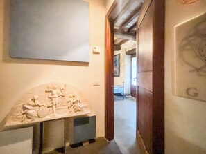 Un pasillo con una escultura de mármol, una cama y una puerta que da a otra habitación.