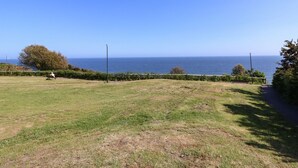 A grassy park with a bench and a path leading to the sea. - The Pines (Bournemouth)