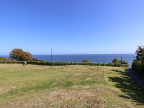 A grassy park with a bench and a path leading to the sea. - The Pines (Bournemouth)