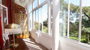 A room with a large window, a wooden table, and a lamp. - The Pines (Bournemouth)