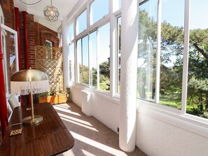 A room with a large window, a wooden table, and a lamp. - The Pines (Bournemouth)