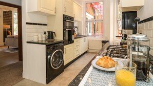 A modern kitchen with a built-in washer, oven, and stove. - The Pines (Bournemouth)