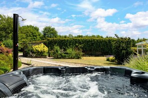 Ein Whirlpool in einem Garten mit blauem Himmel und üppiger Vegetation.