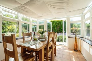 Ein Wintergarten mit Holztisch, Stühlen und einer Blumenvase.