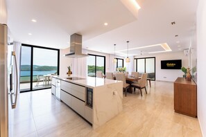 Una cuina moderna amb una illa gran, zona de menjador i vista al mar.