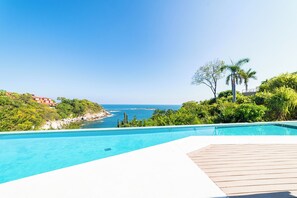 Ein Pool mit Blick auf das Meer und viel Grün.