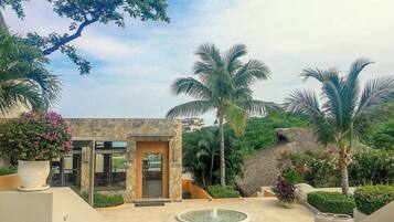 A building with a stone facade, a palm tree, and a fountain in the foreground.