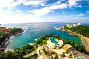 A coastal resort with a swimming pool, beachfront, and lush greenery.