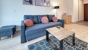 A modern living room with a grey sofa, matching ottoman, a wooden coffee table, and a patterned rug. - RentPlanet - Apartament Triventi (Karpacz)