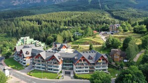 A modern hotel complex with multiple buildings, surrounded by dense forest and mountains. - RentPlanet - Apartament Triventi (Karpacz)