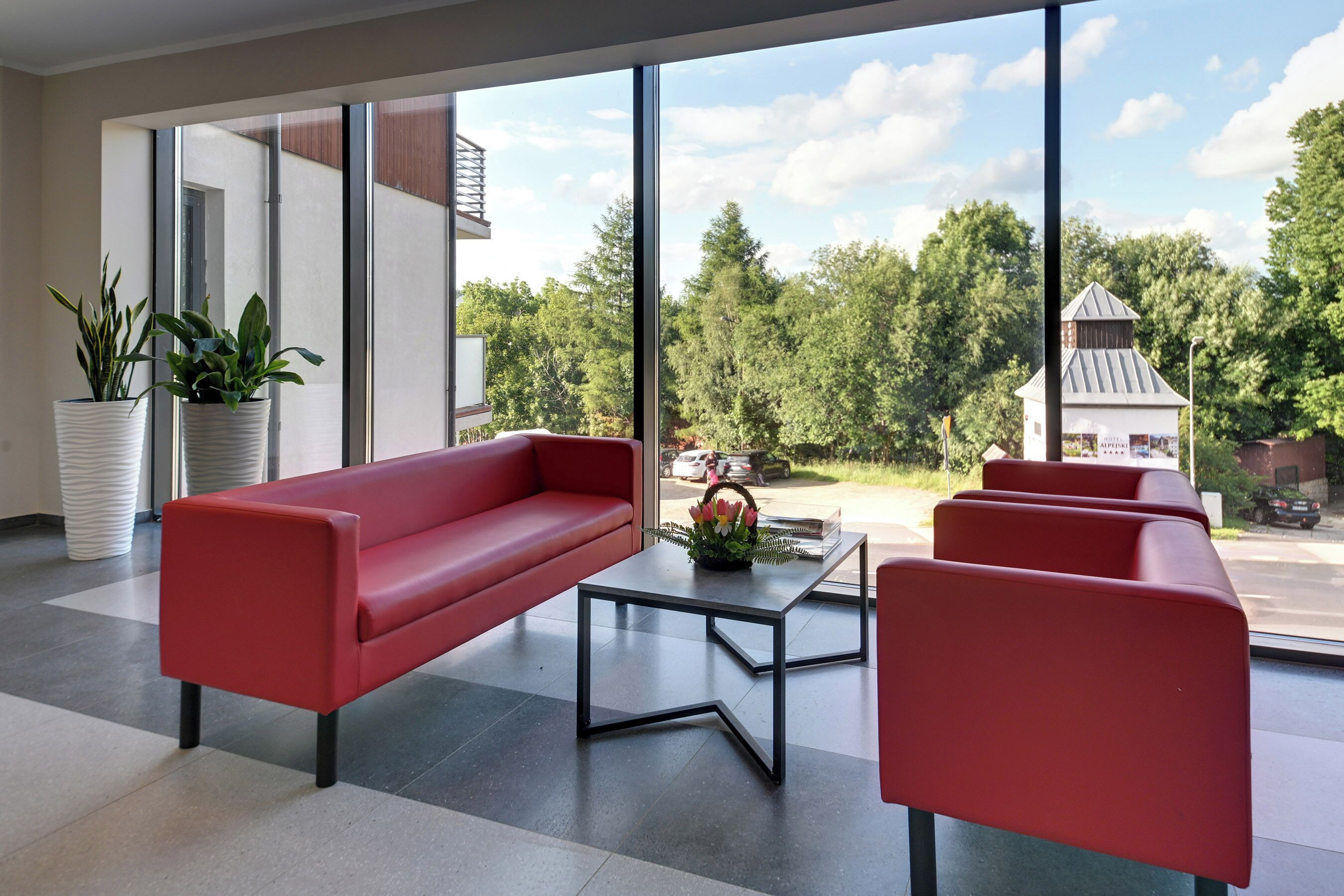 Ein modernes Interieur mit einem roten Sofa, einem Couchtisch und Blumentöpfen.