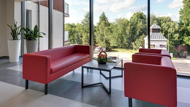 Un interior moderno con un sofá rojo, una mesita de centro y plantas en macetas.
