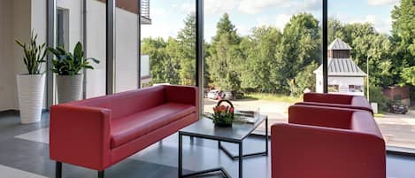 Un interior moderno con un sofá rojo, una mesita de centro y plantas en macetas.