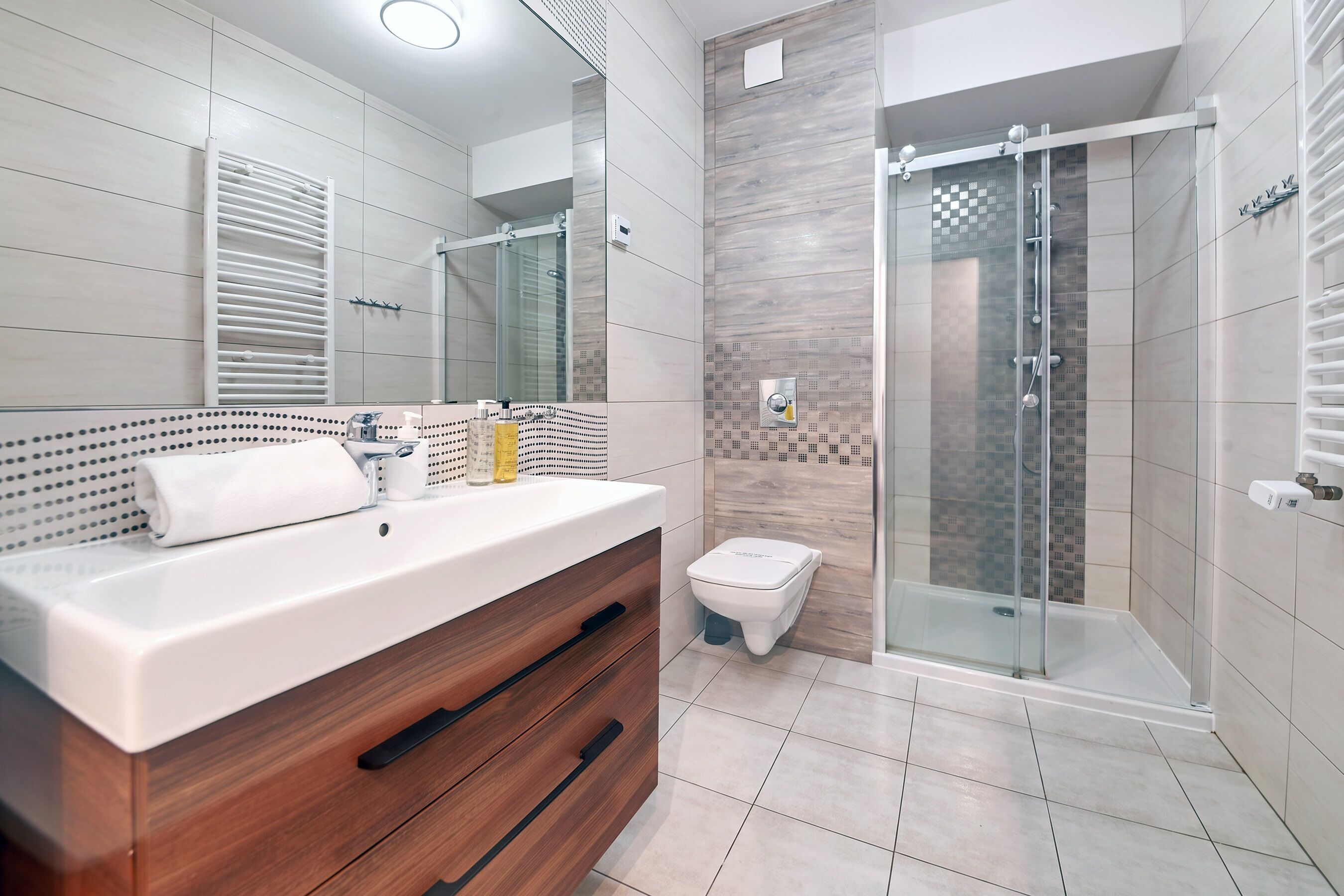 Un baño moderno con tocador de madera, cabina de ducha de vidrio y un inodoro.