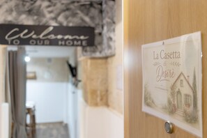 Eine Holztür mit einem Schild, auf dem 'La Casetta di Desire' steht, und einem Willkommensschild darüber.